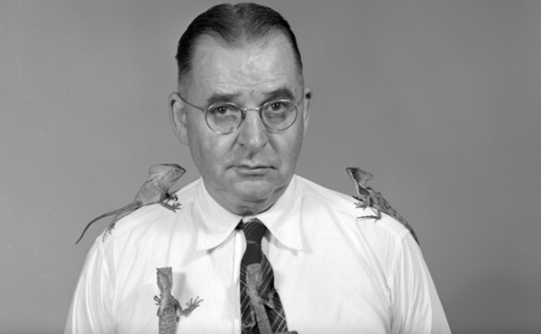 Black and white photo of man with lizards on shoulders